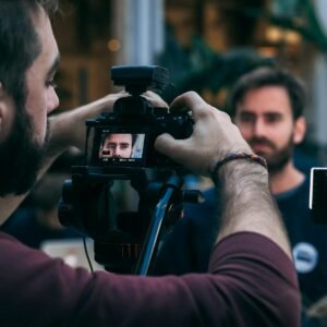 man taking video of standing man wearing black crew-neck top